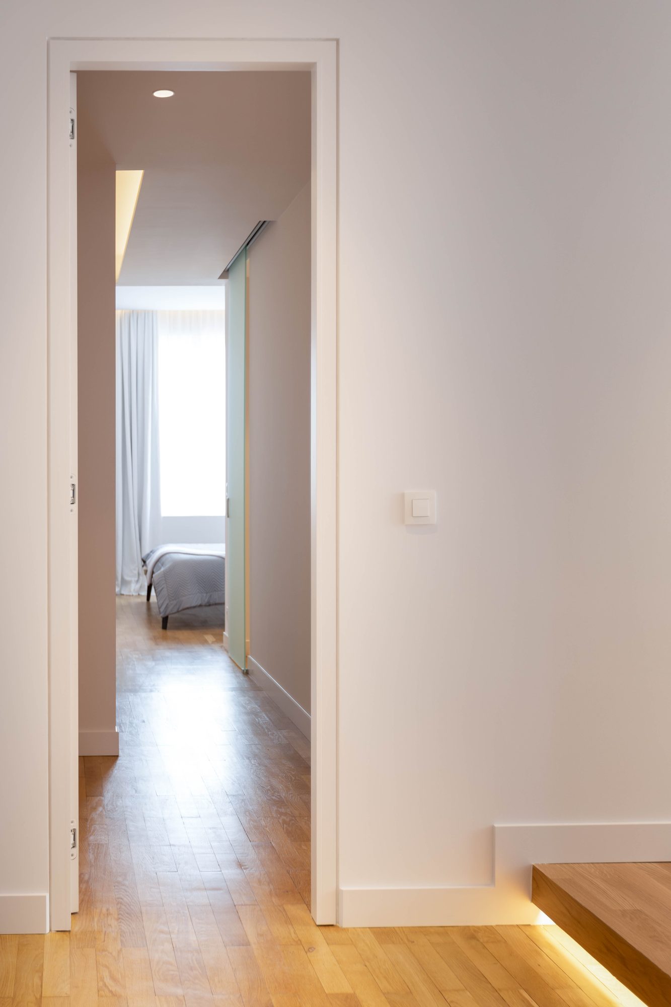 Brugmann 17 — L'enfilade vers la chambre — la marche soulignée de lumière