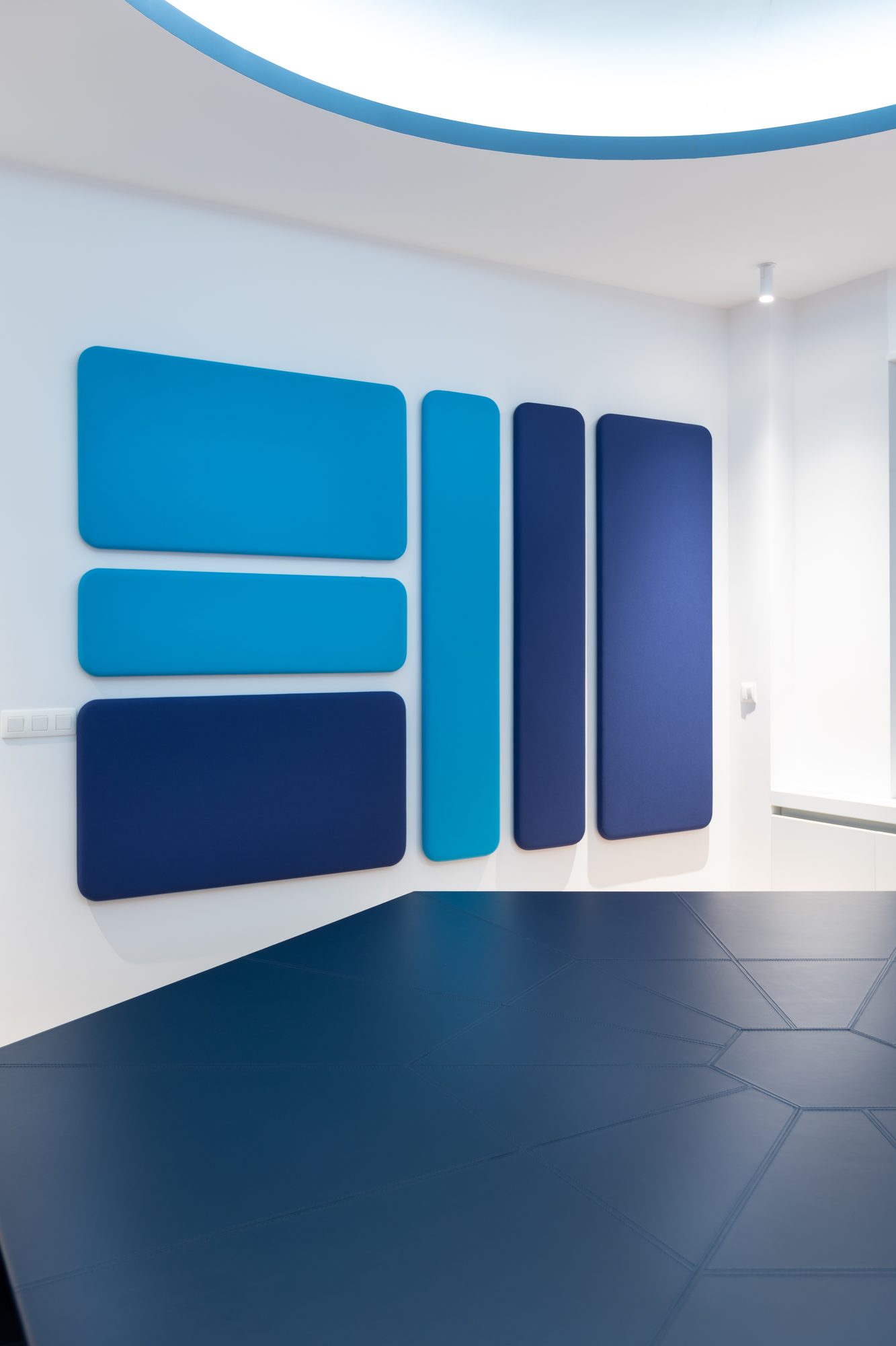 Brugmann 421 — Le mur acoustique — panneaux capitonnés en trois bleus, sol cuir hexagonal
