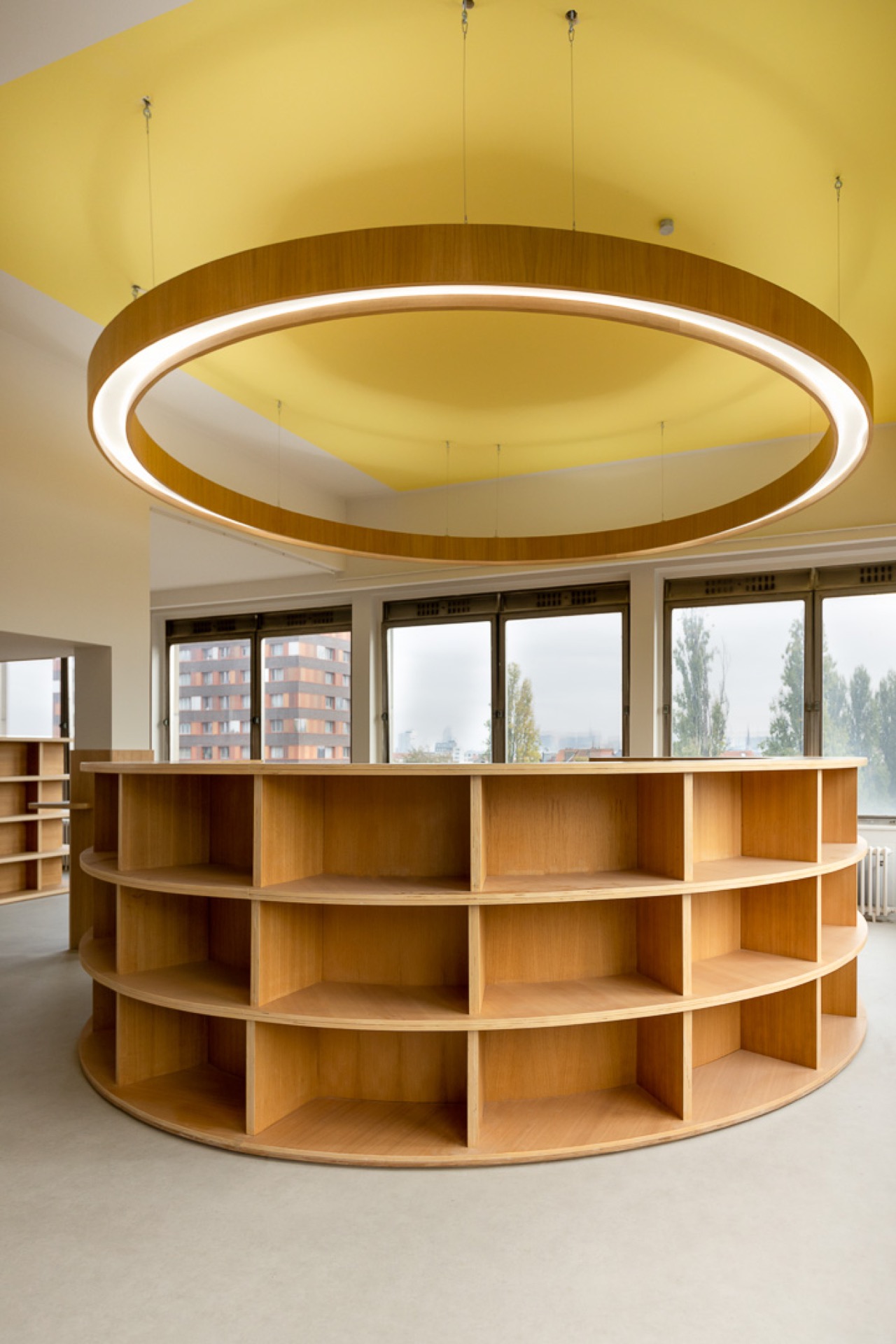 Da Vinci — salle ronde panoramique, anneau-luminaire bois suspendu sous coupole jaune solaire, bibliothèque circulaire chêne, vue urbaine