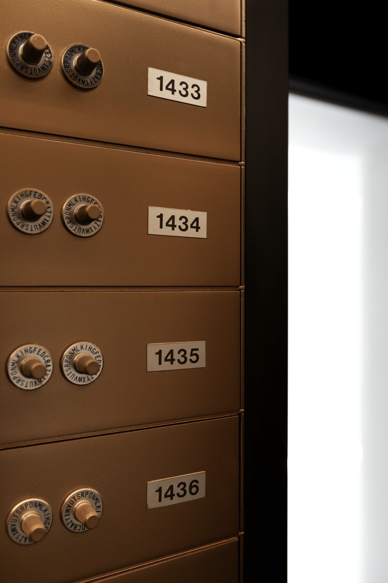 The Vault — Coffres numérotés, molettes à alphabets — lumière cuivrée rasante