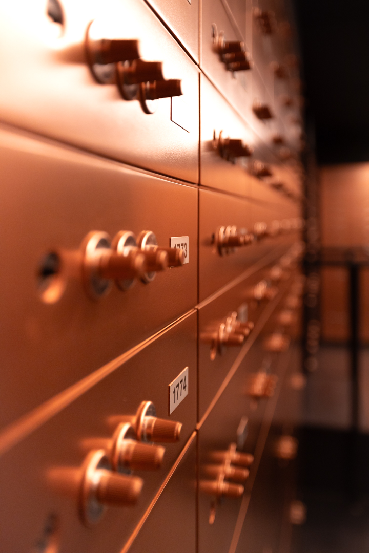 The Vault — Rangées de serrures cuivrées, netteté posée sur un seul coffre