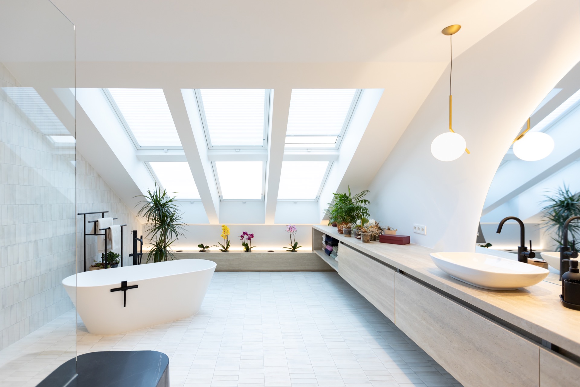 Vanneaux — salle de bain mansardée sous triple verrière, baignoire îlot blanche, voûte courbe et orchidées